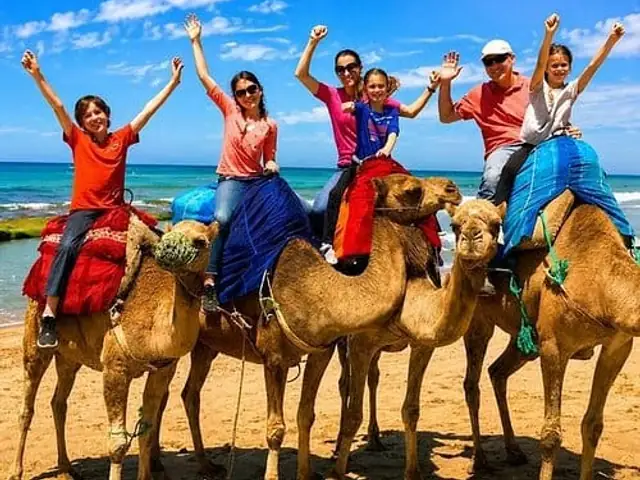 A family riding camels on a beach by the sea