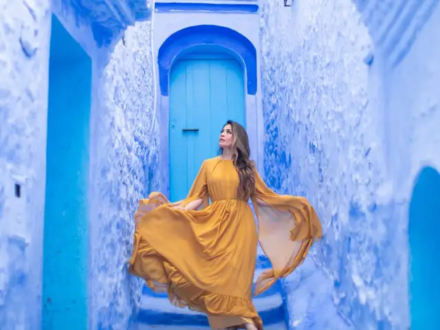 A traveller in a yellow dress on a blue stairway in Chefchaouen