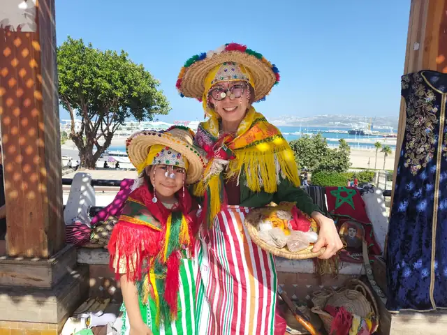Guests in traditional Jebli straw hats and shawls at a viewpoint over the Bay of Tangier